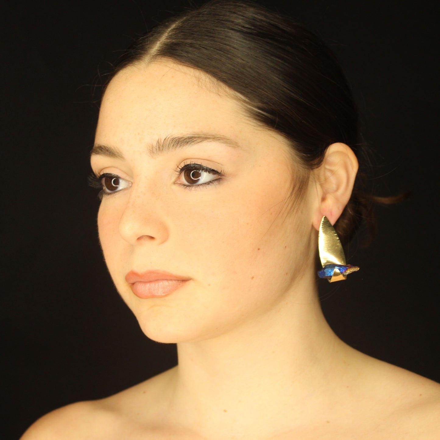 Fashion asymmetrical gold earrings leaf with a blue stone.