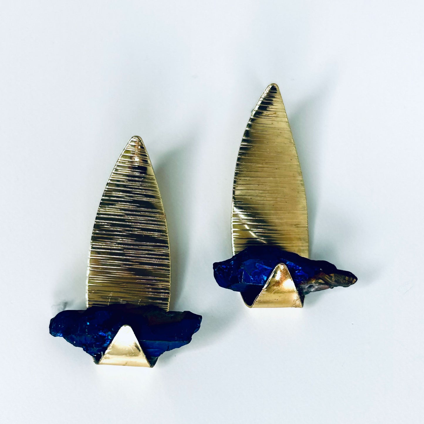 Fashion asymmetrical gold earrings leaf with a blue stone.