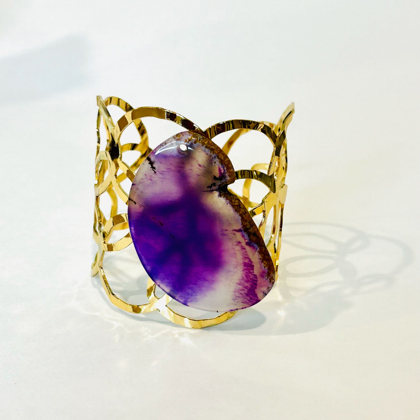Gold fashion cuff bracelet with a purple stone.
