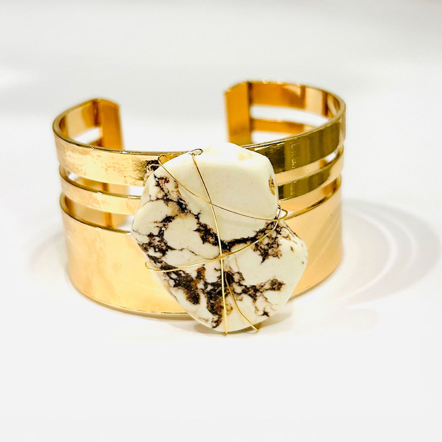 Fashion cuff gold bracelet with a natural white brown spots stone.