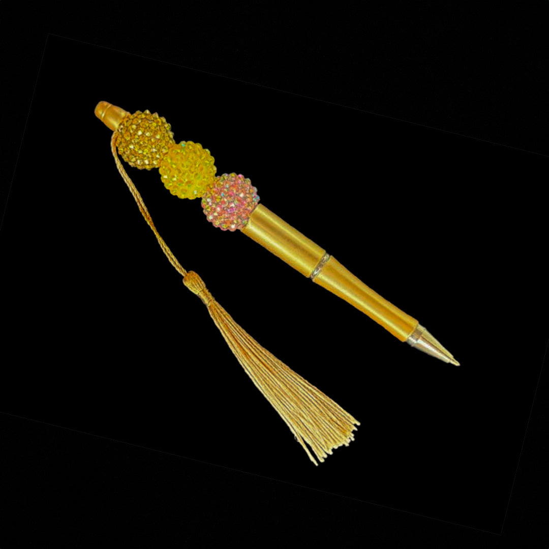 Gold pen with beads and tassel .
